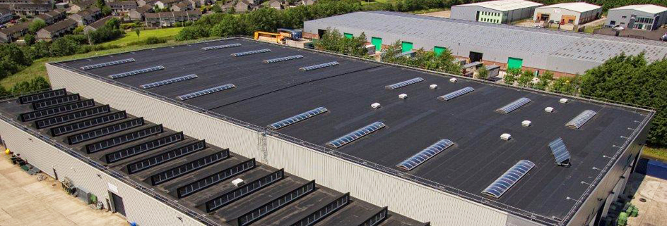 Completed EPDM rubber flat roof installation on a large commercial building, showing heat-welded seams and rooflights